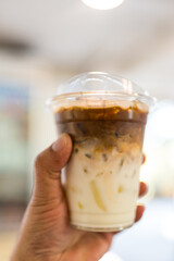 Ice latte coffee in plastic cup with two layer in coffee shop or cafe.