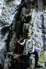 A determined hiker stands confidently with a trekking pole inside a rocky canyon, surrounded by rugged cliffs. The scene symbolizes adventure, strength, and the spirit of exploration in nature.
