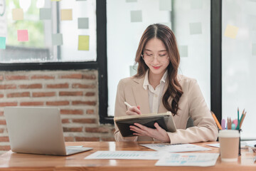 Professional woman engages in creative planning at modern office desk with laptops and colorful notes