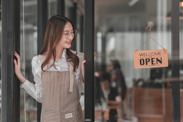 Friendly barista welcomes customers with an open sign at a cozy café