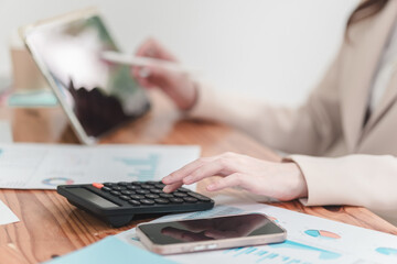 Business professional analyzing financial data with calculator and tablet on wooden desk