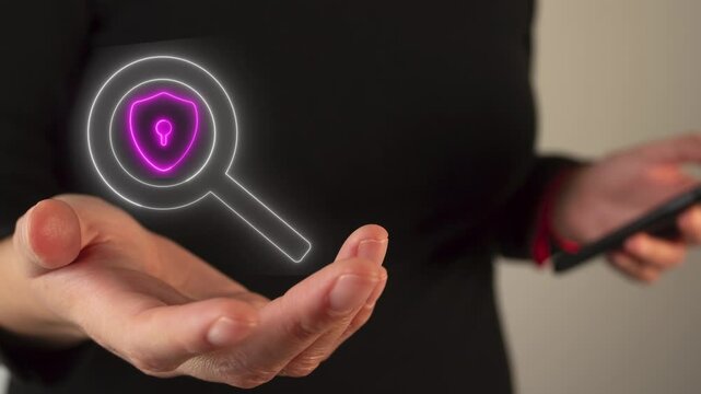 Woman's hand holding a virtual icon of a magnifying glass and a shield