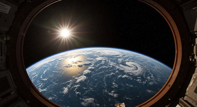 Earth view from space station window, with sun shining brightly above the planet's horizon.