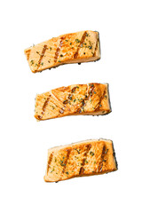 Three perfectly grilled salmon fillets seasoned with herbs and spices isolated on transparent...