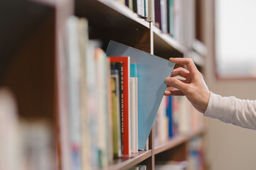 right hand choosing and picking book in public library.