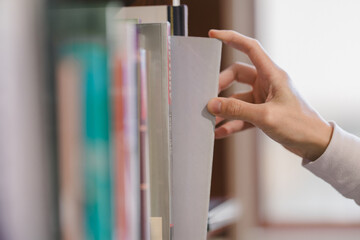 right hand choosing and picking book in public library.