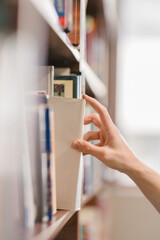 right hand choosing and picking book in public library.