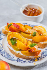 Bruschetta with ricotta cheese, sliced nectarines, basil and honey on a plate