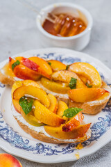 Bruschetta with ricotta cheese, sliced nectarines, basil and honey on a plate
