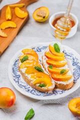 Bruschetta with ricotta cheese, sliced nectarines, basil and honey on a plate