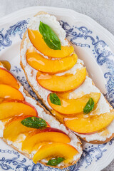 Bruschetta with ricotta cheese, sliced nectarines, basil and honey on a plate