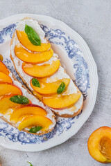 Bruschetta with ricotta cheese, sliced nectarines, basil and honey on a plate