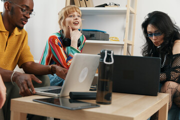 young adult woman and colleagues working together in modern workplace socializing and collaborating...