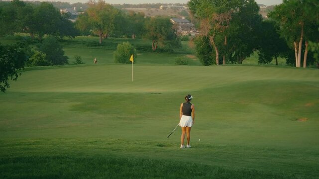 Amateur female golfer playfully pretends to cheat on a par three by throwing her golf ball instead of hitting it. The clip captures a lighthearted, humorous moment during a relaxed round.