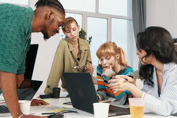 Young adult woman and male colleagues collaborating in modern workplace, socializing and working as...