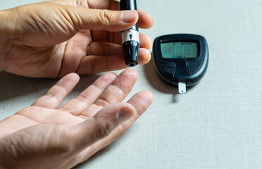 Woman's hands checking diabetes and hyperglycemia with digital blood sugar meter. Healthcare and...