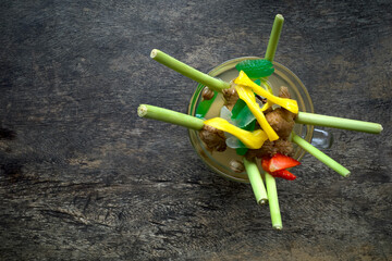 A glass of herbal drink with lemongrass, tea, ginger, honey and strawberry topping