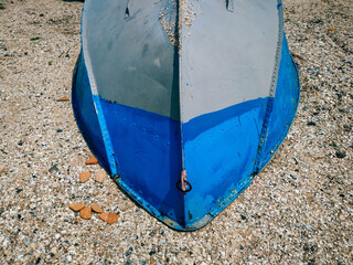 An overturned grey-blue boat lies on the seashore. The concept of bad weather, storm and windless...