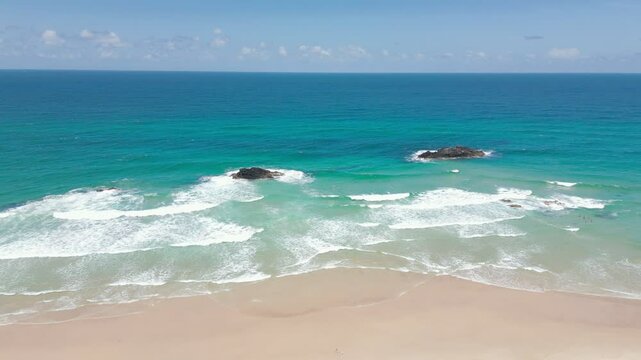 Blue waves rolling in against the golden sand.