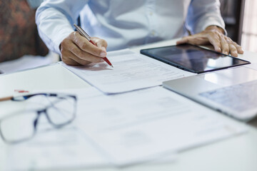 asian businessman checking document and business contract using tablet and laptop working on desk in office