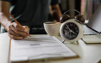 asian man work at home checking report document using laptop working in a hurry before end time in a day, time management concept, routine work, office hour