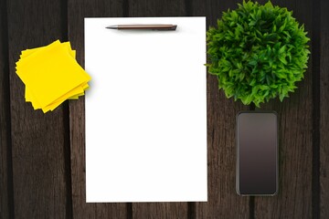 Paper on table in front of plant and smartphone