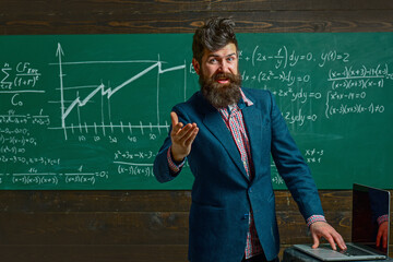 Teacher explains math in class. Professor in classroom on math lesson. School teacher writes math formula. Funny teacher. Professor teaching lesson in classroom. Teacher explains math. Teachers day.