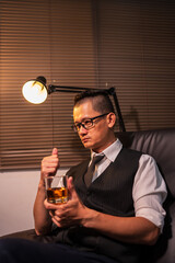 Businessman holding a glass of whiskey, sitting and drinking	