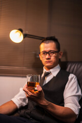 Businessman holding a glass of whiskey, sitting and drinking	