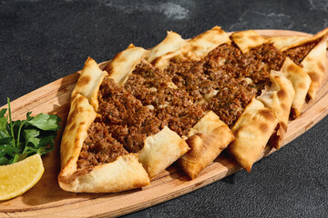 Beef pide with golden crust in bright overhead composition, Turkish flatbread with minced meat...