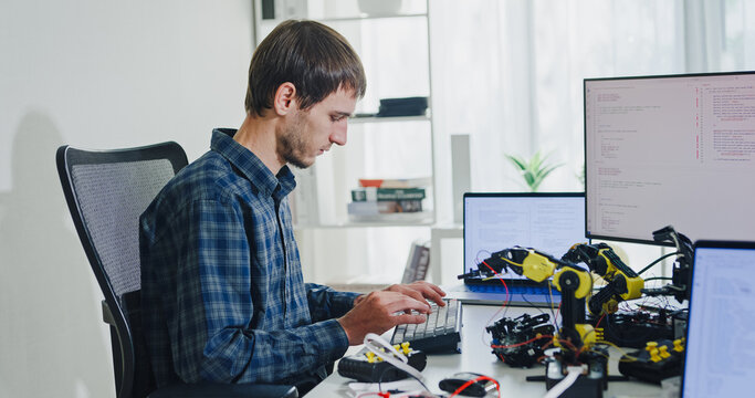 Young adult male freelance developer typing write prompt AI bot app program nomad terminal with coding at office. Artificial intelligence dashboard, robotics, user interface, machine learning concept.