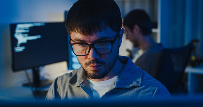 Closeup team adult male freelance work late typing write prompt AI bot app program nomad terminal code at office night. Artificial intelligence dashboard, robotics, user interface, machine learning.