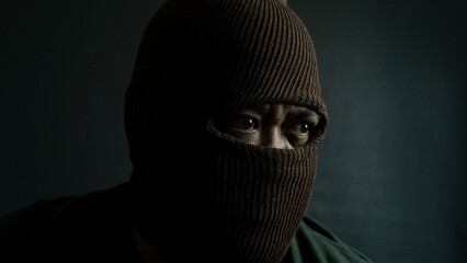 Male subject with brown fabric eye mask fully worn on face, isolated on black, suggesting secrecy,...