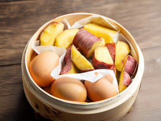 Boiled eggs and sweet potatoes in a bamboo steamer