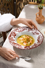 Fish soup bowl in bright natural lighting, overhead composition on rustic linen table