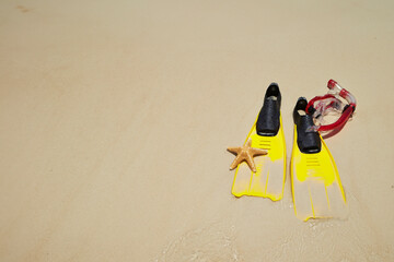 Obraz premium Yellow flippers, snorkel set and starfish on the beach