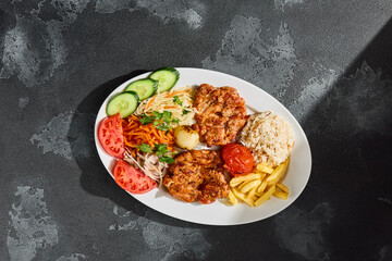Grilled chicken fillet platter in bright overhead rustic composition with rice, vegetables, and fries