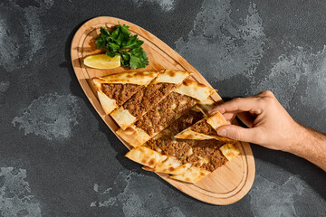 Beef pide Turkish flatbread with minced meat, bright lighting, overhead composition on wooden board