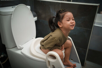 happy toddler girl is sitting on the toilet at home. potty training and learning