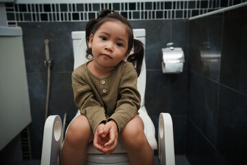 happy toddler girl is sitting on the toilet at home. potty training and learning