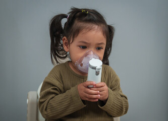 toddler girl making inhalation treatment with nebulizer
