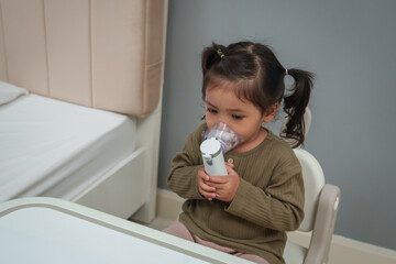 toddler girl making inhalation treatment with nebulizer at home