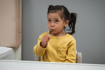 toddler girl takes syrup medicine with syringe by herself. sick child