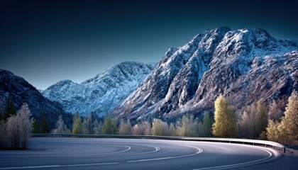 Winding road through snowy mountains at dawn