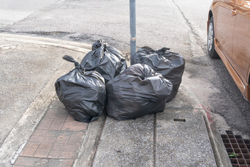 Garbage in black garbage bag in stack at garbage dump on footpath taken in downtown area