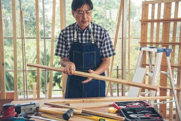 DIY craftsperson asian man working wood heap carpenter objects woodwork desk. Architect man hands...