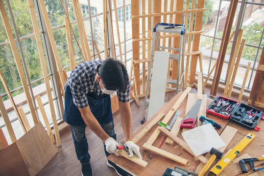 DIY craftsperson asian man working wood heap carpenter objects woodwork desk. Architect man hands use ruler measure hammer home improvement. Wooden builder carpenter repairing construction workshop