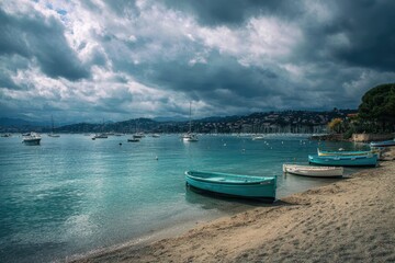 Serene coastal scene with teal boats on sandy beach, under dramatic, grey skies, overlooking a calm bay dotted with sailboats and distant hills