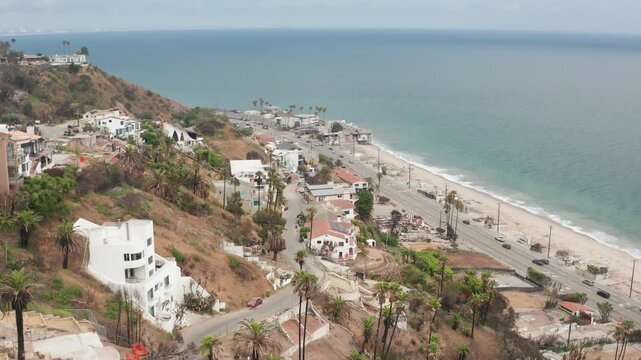 Low aerial shot flying over burned properties on the hillside along Pacific Coast Highway at Las Flores Canyon after the Palisades Fire in Malibu, California. 4K
