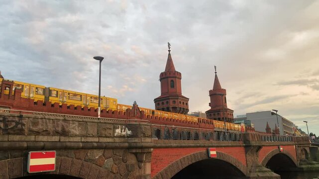 Steady clip of a red brick bridge in Berling with two castle belltowers in the background and traffic on the bridge